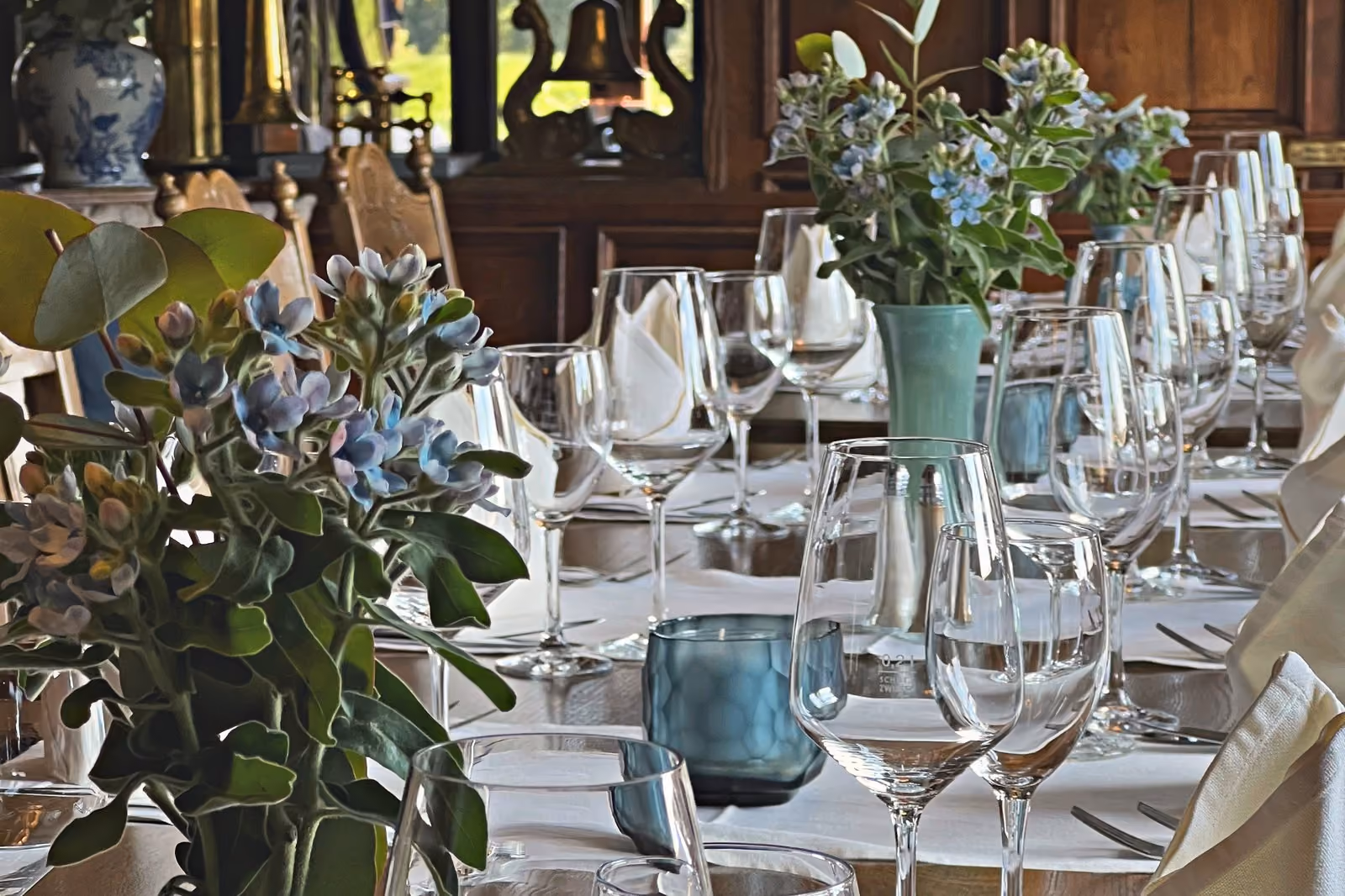 Der Saal festlich gedeckt, blaue Blumen und Gläser in Reihen