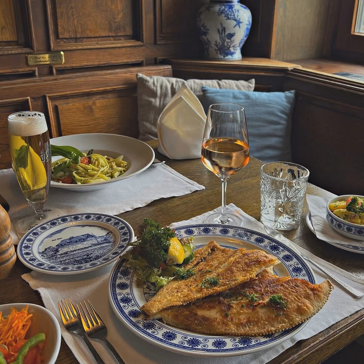 Mehrere Fischgerichte auf Delft-Tellern auf einem gedeckten Tisch