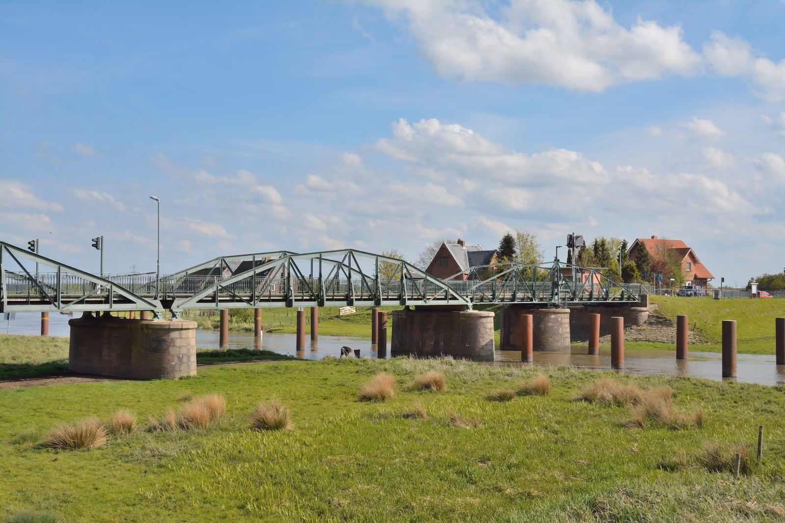 Die Klevendeicher Drehbrücke über der Pinnau, davor Schafe auf dem Deich